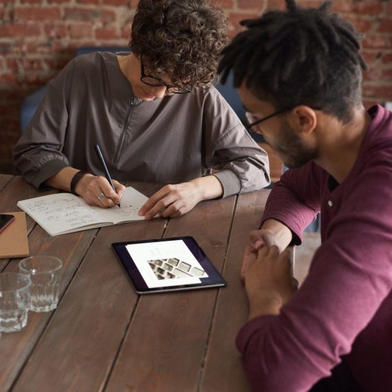 man wearing purple long sleeved shirt looking at the ipad 3184326