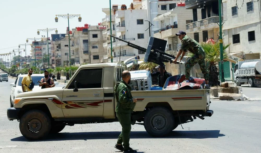 SweidaPersonwearingmilitaryclothingstandsatthebackofavehicleSweidaSyriaJuly252025 492248